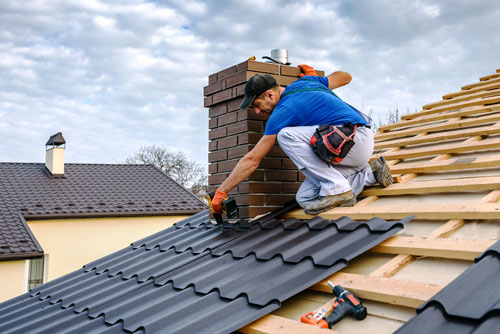 A man installing metal roofing on a roof.