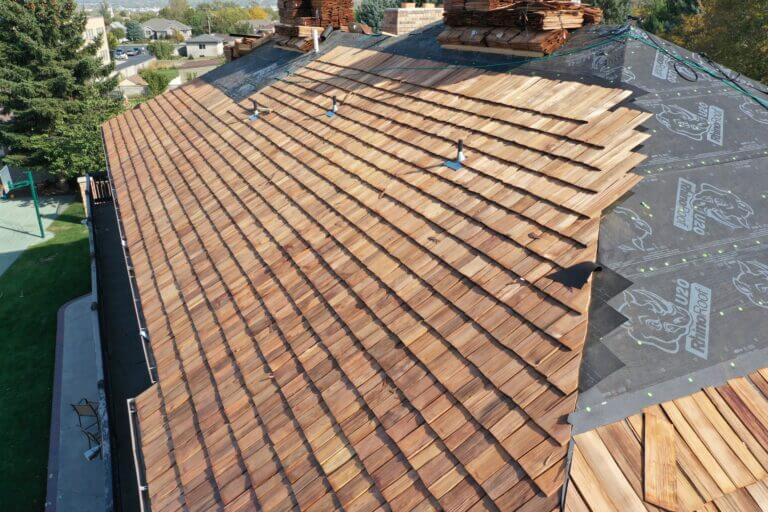 A roofing contractor working on a roof with wooden shingles. Image by Cedar Shake Roofing Company in Salt Lake City, Utah.